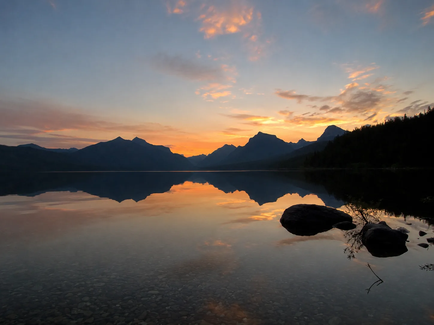 Sunset over Lake McDonald from Apgar Beach with mountains reflected in calm water